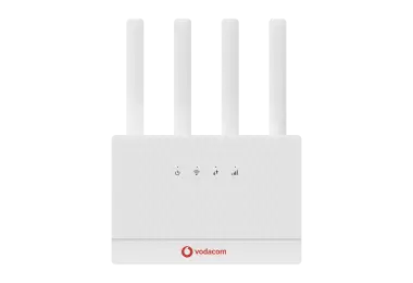 A front-facing view of a white Vodacom Home Internet S90 router. The device features a textured rectangular body with four upright external antennas. Four circular LED indicator icons are centered on the front face, representing power, Wi-Fi, data transfer, and signal strength. The red Vodacom logo is positioned at the bottom center.