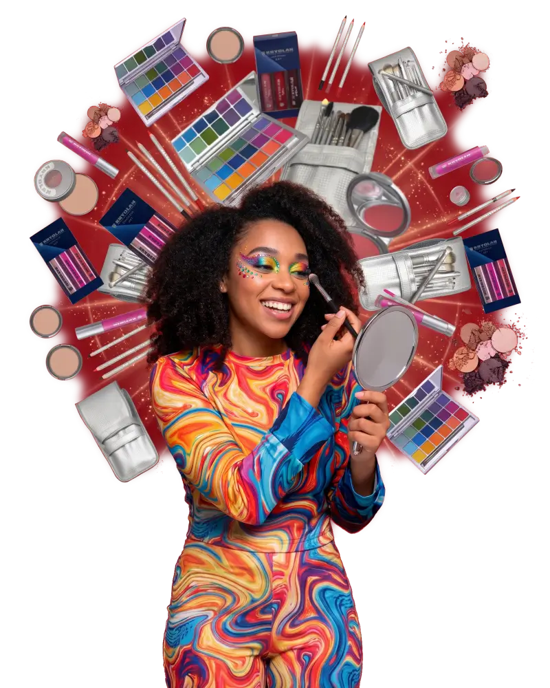 Woman applying makeup with hand mirror, surrounded by Kryolan palettes, makeup brushes, and cosmetics.